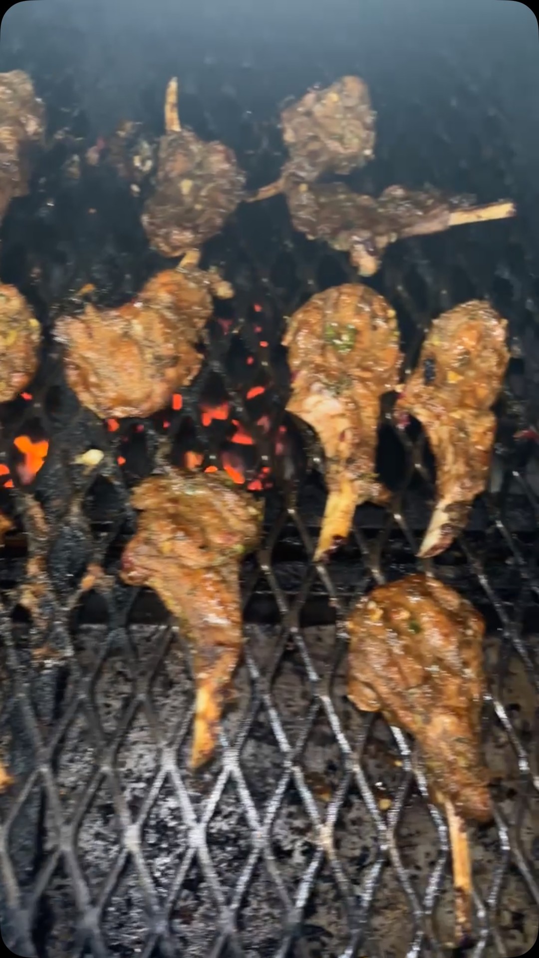 Jerk chicken grilling over charcoal with glowing embers
